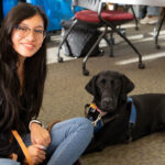 Chemistry major Monserrat Martinez-Garcia, a senior, and her Guiding Eyes pup Nia sitting on the floor for a picture. Photos by Lily Rand