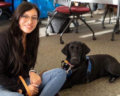 Chemistry major Monserrat Martinez-Garcia, a senior, and her Guiding Eyes pup Nia sitting on the floor for a picture. Photos by Lily Rand