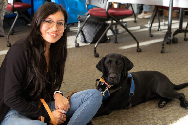 Chemistry major Monserrat Martinez-Garcia, a senior, and her Guiding Eyes pup Nia sitting on the floor for a picture. Photos by Lily Rand