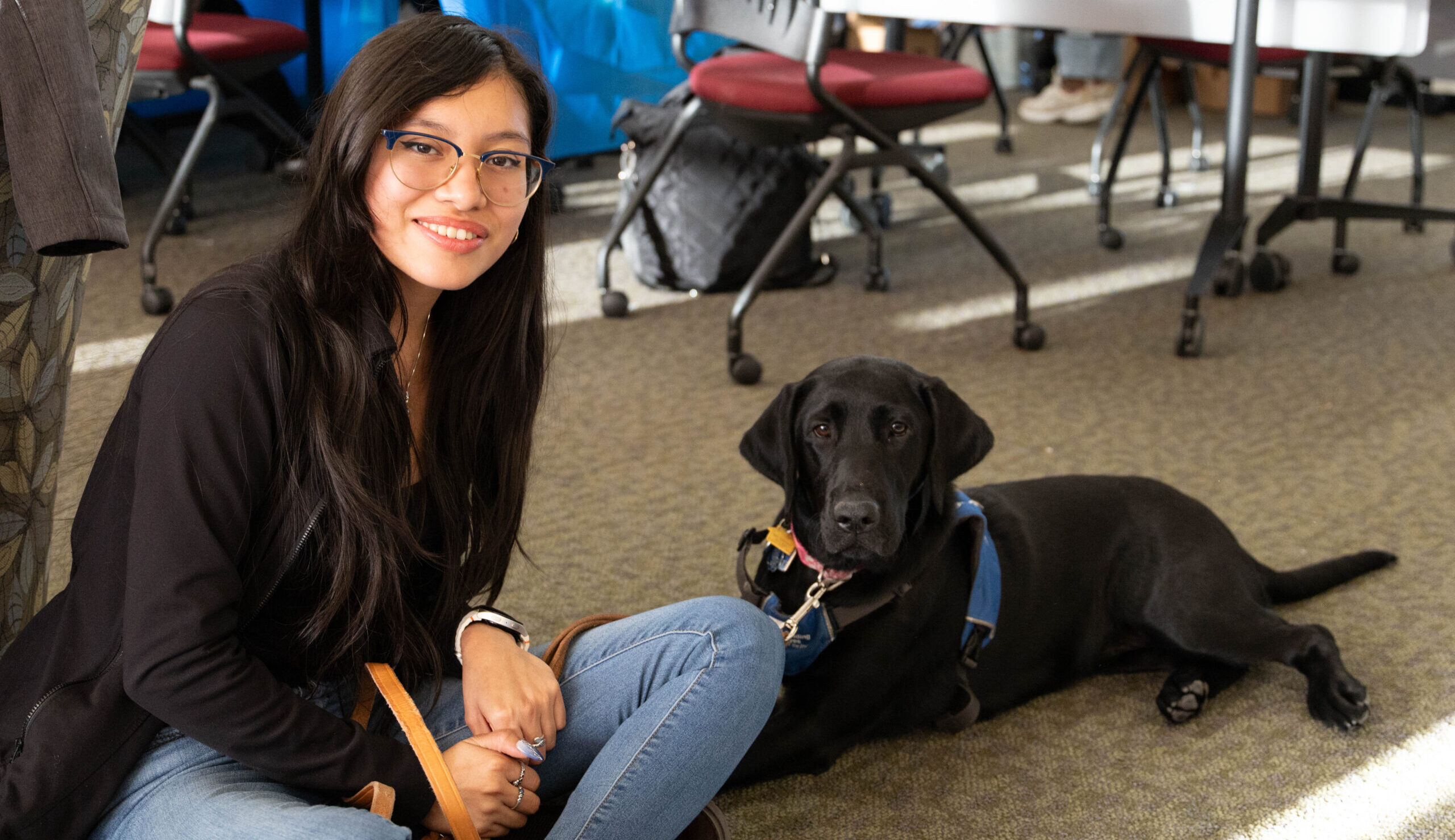 Chemistry major Monserrat Martinez-Garcia, a senior, and her Guiding Eyes pup Nia sitting on the floor for a picture. Photos by Lily Rand