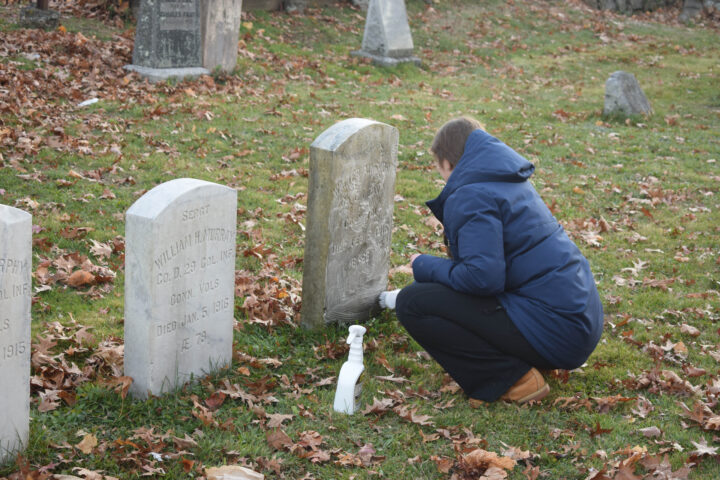 A student volunteer cleans a headstone in the Westville Cemetery on Nov. 20. Photos by Lily Rand